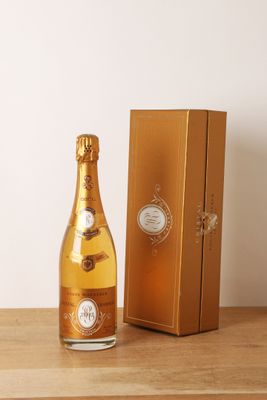 une image représentant une bouteille de champagne posée à côté d'un coffret doré
