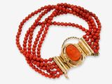 un collier de perles rouges muni d'un fermoir en or et d'un pendentif en pierre rouge