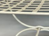 a white metal table with a basket on top of it