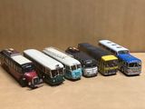 beaucoup de petits bus en jouet alignés sur une table