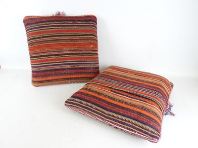 deux coussins rayés aux couleurs vives posés l'un à côté de l'autre sur une surface blanche