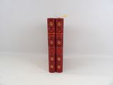 two red books sitting on top of each other on a white surface