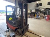 a forklift in a warehouse with a lot of pallets on the floor