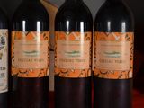 three bottles of red wine are lined up on a table