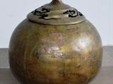 un grand vase en bronze posé sur un sol carrelé