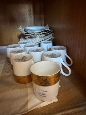 Plusieurs tasses à café sont alignées sur une étagère dans une cuisine
