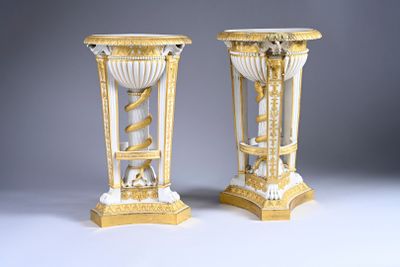 pair of gold and white vases sitting on top of a white table