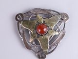 une broche en argent sertie d'une pierre rouge