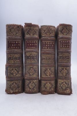 six vieux livres sont alignés sur une surface blanche