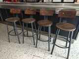 trois tabourets en bois sont assis devant un bar
