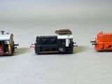 trois petits trains assis côte à côte sur une surface blanche