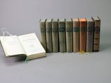 several old books are lined up in a row on a gray surface