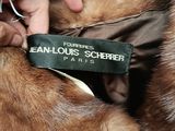 a person that is holding a fur coat with a tag on it