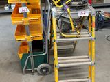 une échelle posée à côté d'un chariot sur lequel se trouvent des outils