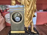 a gold statue of a man holding a clock on a marble base
