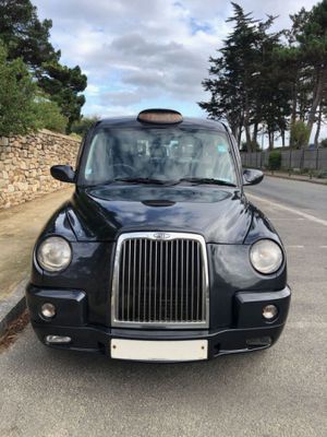 black cab parked on the side of the road in front of a stone wall