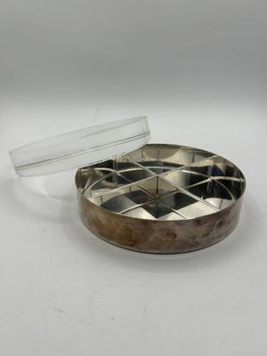 un gros plan d'un récipient métallique muni d'un couvercle, posé sur une surface blanche