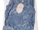 a close up of a blue shirt in a plastic bag on a white background