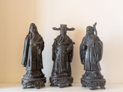 trois statues noires représentant des personnes debout côte à côte sur une table