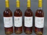 quatre bouteilles de vin sont alignées sur une surface grise