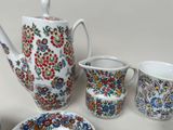 a tea pot, cups and saucer sitting on a table