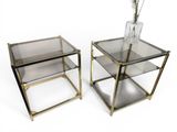 pair of brass and glass side tables with a vase on top