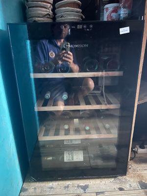 a man taking a picture of himself in a wine cooler