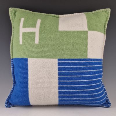 un oreiller vert et bleu sur lequel figure un « h » blanc