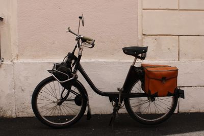 a bicycle with a basket on the back parked next to a building