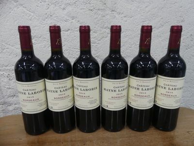 six bouteilles de vin rouge sont alignées sur une table en bois