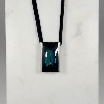 un collier avec une pierre verte montée sur un cordon noir