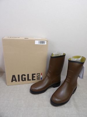 une paire de bottes en cuir marron posée sur une table, à côté d'une boîte