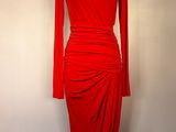 La robe rouge est posée sur un présentoir à mannequin devant un mur blanc.