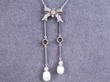 a close up of a necklace with pearls and a bird on it