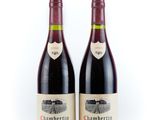 two bottles of red wine sitting next to each other on a white surface