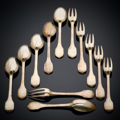 Plusieurs fourchettes et cuillères sont disposées en cercle sur une surface noire.