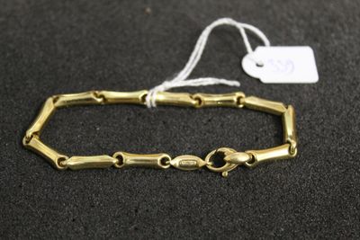 gros plan d'un bracelet en or sur une surface noire