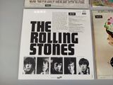 three rolling stones albums on display on a table in front of a newspaper