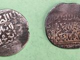 two silver coins with arabic writing on them on a green surface