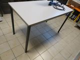 une table blanche sur laquelle est posé un ordinateur portable, dans une pièce