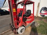 a red forklift truck parked in front of a building