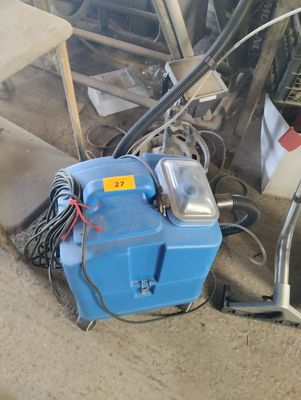 a blue machine that is sitting on the ground next to a pile of junk