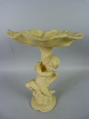 une petite statue représentant un garçon tenant un abreuvoir à oiseaux sur un socle