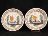 two plates with boats painted on them on a black background