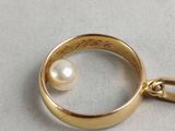 a gold ring with a pearl hanging from it ' s side