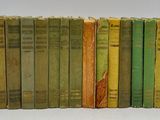 several old books are lined up in a row on a white surface
