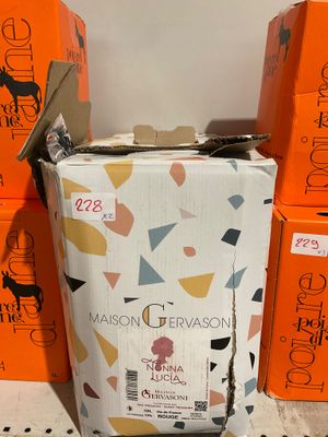 Plusieurs cartons de vin sont empilés les uns sur les autres par terre.