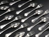 beaucoup de cuillères et de fourchettes en argent posées sur une table noire
