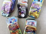 six different pokemon tins are lined up on a couch