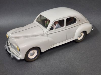 une petite voiture blanche avec un homme au volant